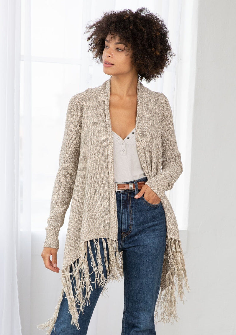 [Color: Natural/Cream] A front facing image of brunette model wearing a marled knit cardigan with a fringe hem, shawl collar, and a cozy, relaxed fit. A versatile fall cardigan. 