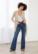 [Color: Natural/Cream] A front facing image of brunette model wearing a marled knit cardigan with a fringe hem, shawl collar, and a cozy, relaxed fit. A versatile fall cardigan. 