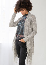 [Color: Black/Off White] A front facing image of brunette model wearing a marled knit cardigan with a fringe hem, shawl collar, and a cozy, relaxed fit. A versatile fall cardigan. 