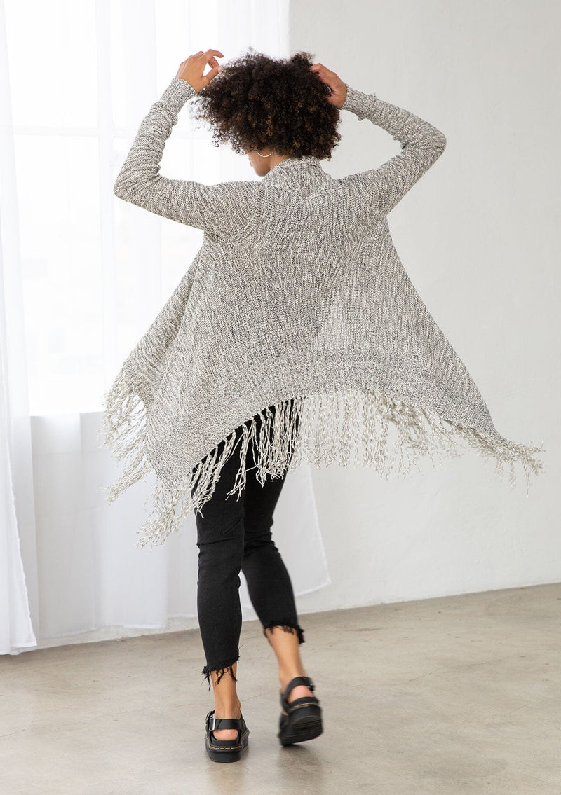 [Color: Black/Off White] A back facing image of brunette model wearing a marled knit cardigan with a fringe hem, shawl collar, and a cozy, relaxed fit. A versatile fall cardigan. 