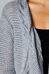 [Color: Grey] A detail image of a brunette model wearing a cozy grey open knit cardigan with a shawl collar, cable knit details, and ribbed trims. A casual fall cardigan for any occasion. 
