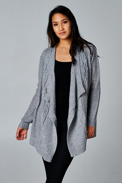 [Color: Grey] A front facing image of a brunette model wearing a cozy grey open knit cardigan with a shawl collar, cable knit details, and ribbed trims. A casual fall cardigan for any occasion. 