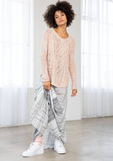 [Color: Blush] A front facing image of a brunette model wearing a lightweight cable knit pullover with open knit details. Featuring a classic round neckline, dropped shoulders, long sleeves, and a shirttail hem. Laid-back boho style for casual outings. 