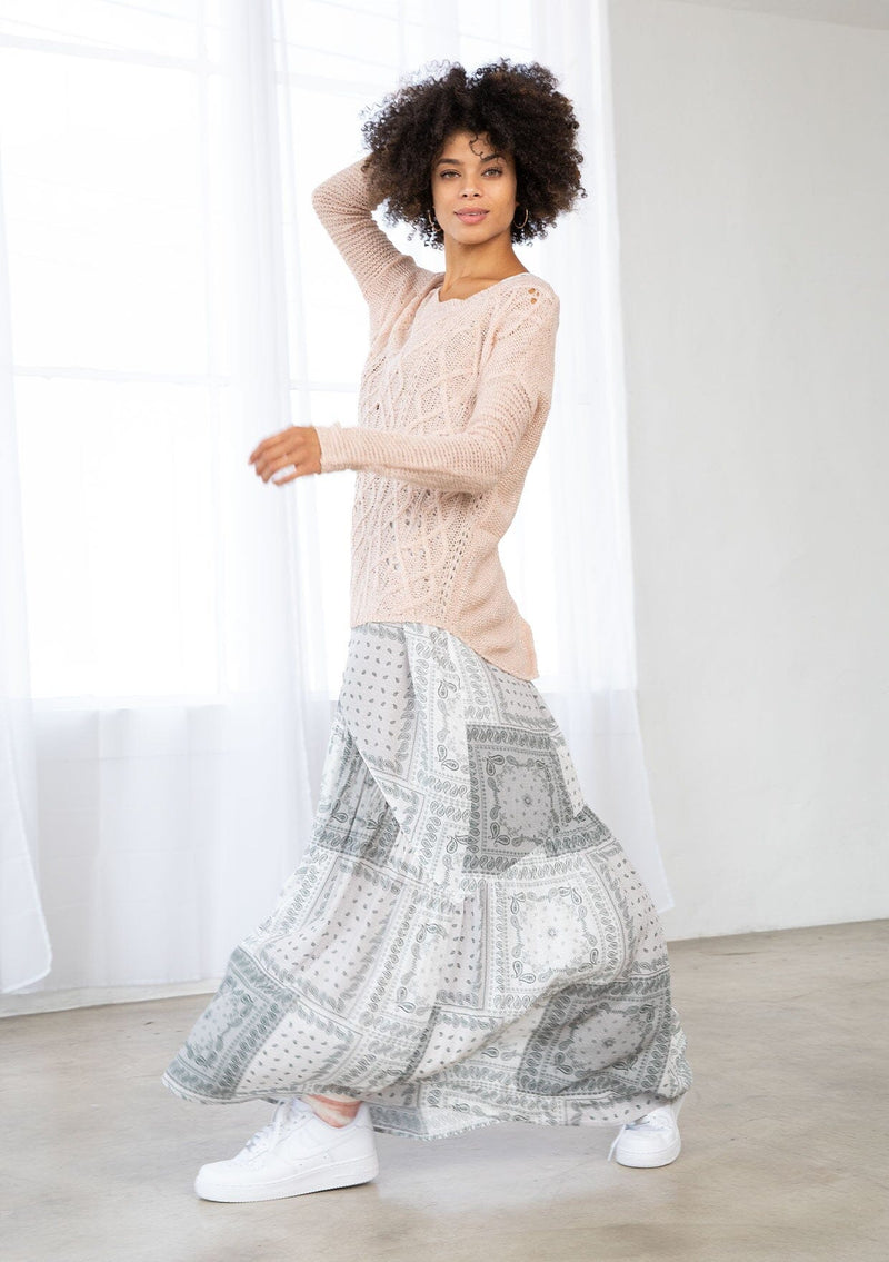 [Color: Blush] A side facing image of a brunette model wearing a lightweight cable knit pullover with open knit details. Featuring a classic round neckline, dropped shoulders, long sleeves, and a shirttail hem. Laid-back boho style for casual outings. 