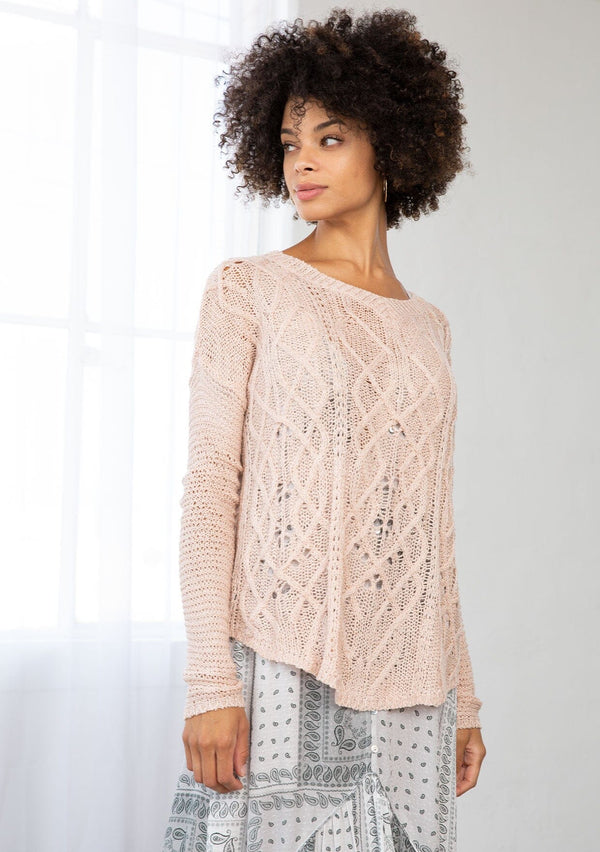 [Color: Blush] A front facing image of a brunette model wearing a lightweight cable knit pullover with open knit details. Featuring a classic round neckline, dropped shoulders, long sleeves, and a shirttail hem. Laid-back boho style for casual outings. 
