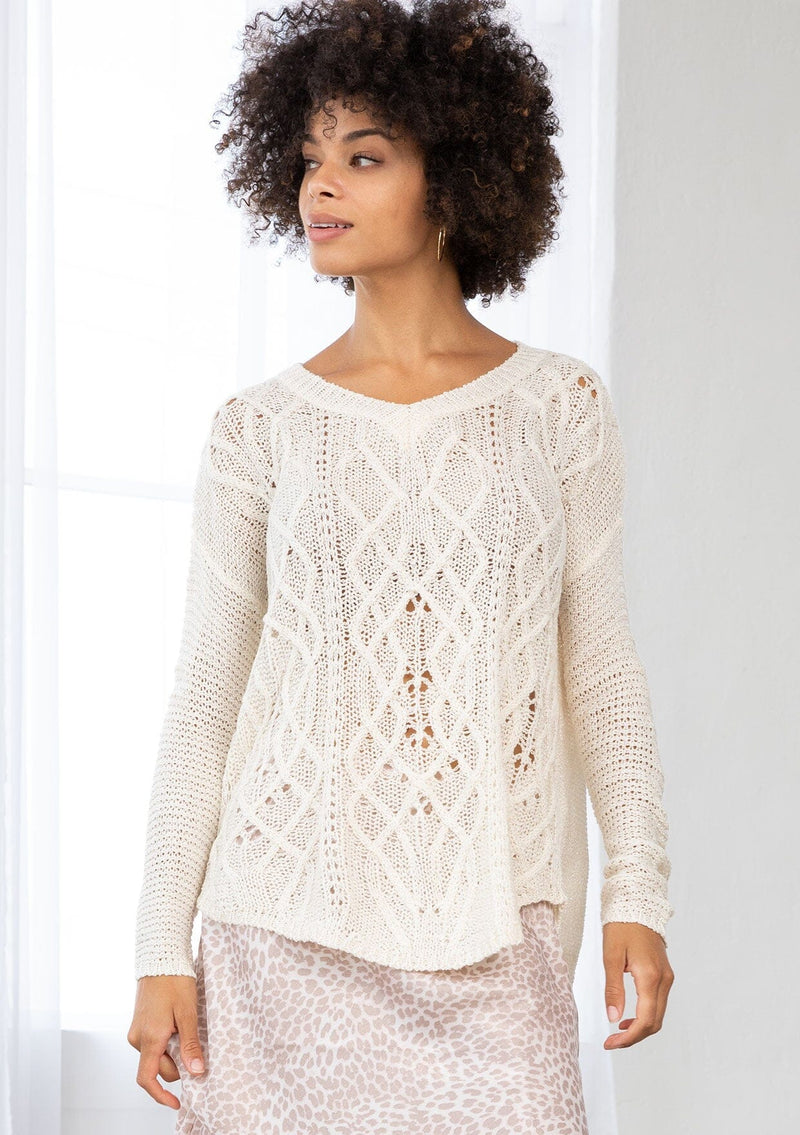 [Color: Vanilla] A front facing image of a brunette model wearing a lightweight cable knit pullover with open knit details. Featuring a classic round neckline, dropped shoulders, long sleeves, and a shirttail hem. Laid-back boho style for casual outings. 