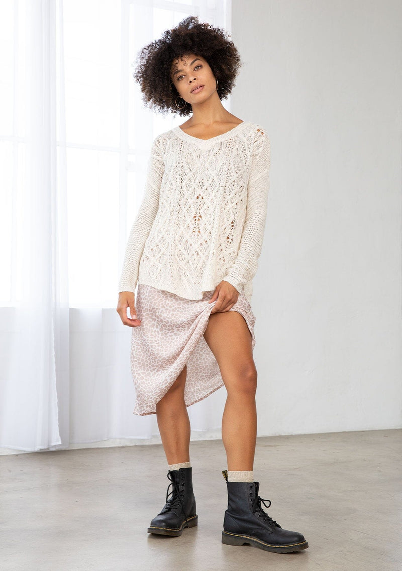 [Color: Vanilla] A front facing image of a brunette model wearing a lightweight cable knit pullover with open knit details. Featuring a classic round neckline, dropped shoulders, long sleeves, and a shirttail hem. Laid-back boho style for casual outings. 