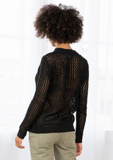 [Color: Black] An image of a brunette model wearing a black crochet pullover sweater with a side zipper accent. Featuring a crew neckline, long sleeves, and rib trim. 