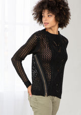 [Color: Black] An image of a brunette model wearing a black crochet pullover sweater with a side zipper accent. Featuring a crew neckline, long sleeves, and rib trim. 