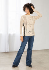 [Color: Natural] An image of a brunette model wearing a beige crochet pullover sweater with a side zipper accent. Featuring a crew neckline, long sleeves, and rib trim. 
