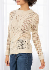 [Color: Natural] An image of a brunette model wearing a beige crochet pullover sweater with a side zipper accent. Featuring a crew neckline, long sleeves, and rib trim. 