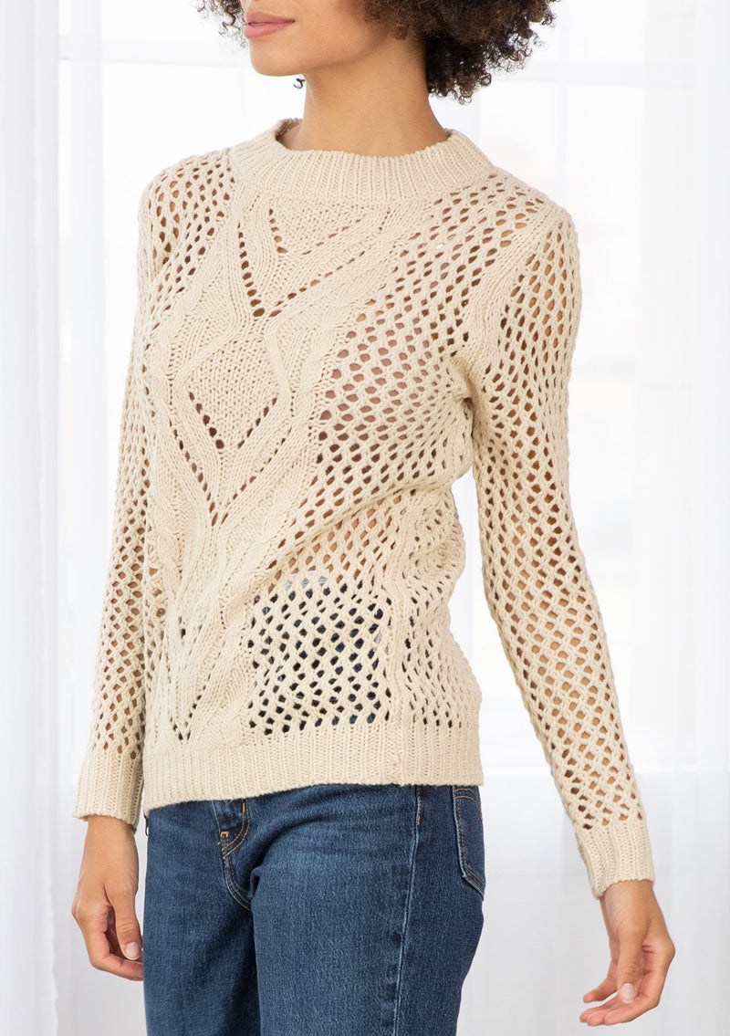 [Color: Natural] An image of a brunette model wearing a beige crochet pullover sweater with a side zipper accent. Featuring a crew neckline, long sleeves, and rib trim. 