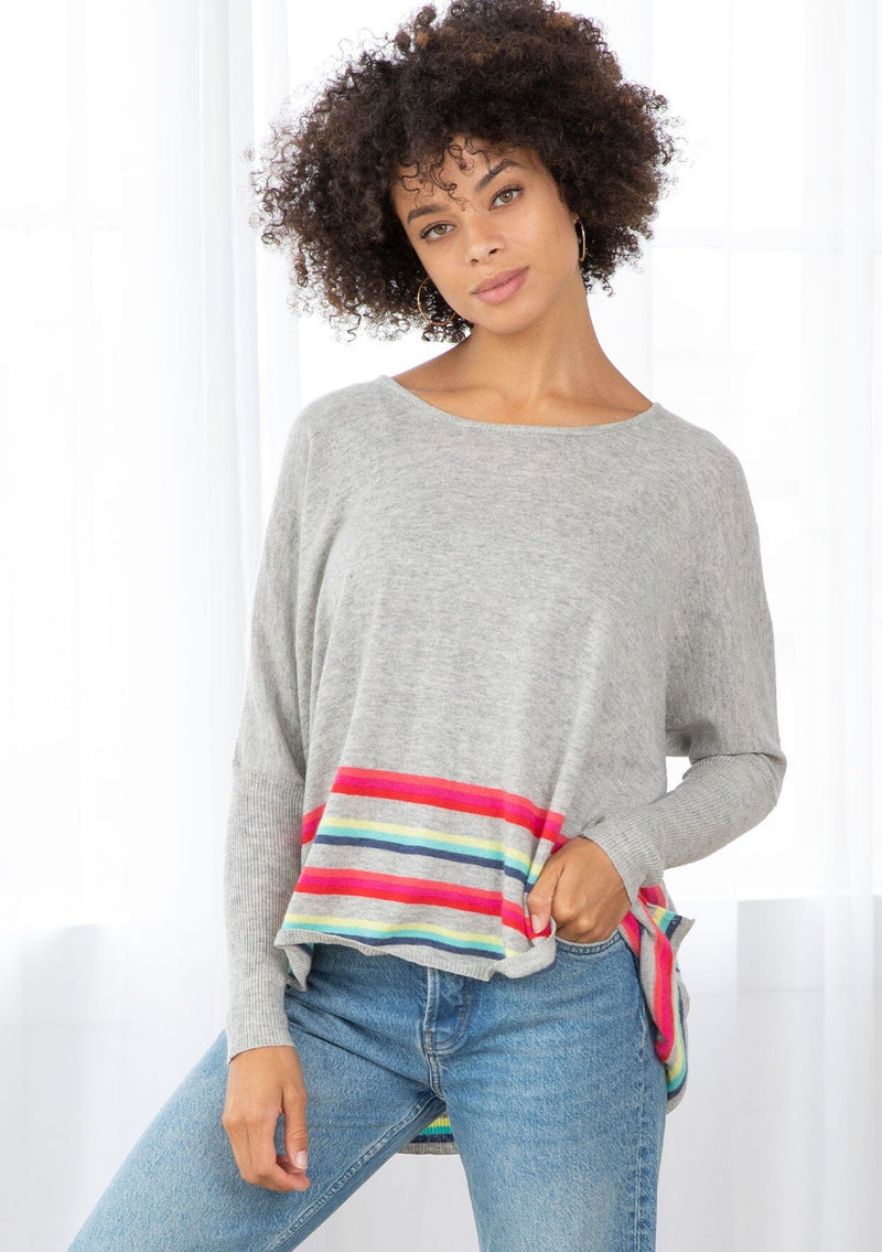 [Color: Silver/Multi] A front facing image of a brunette model wearing a grey pullover with a vibrant stripe accent. Featuring a relaxed fit, long dolman sleeves with tapered  finish, and a flattering round neckline. 