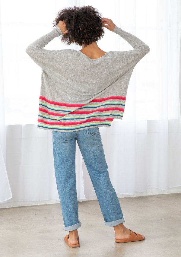 [Color: Silver/Multi] A back facing image of a brunette model wearing a grey pullover with a vibrant stripe accent. Featuring a relaxed fit, long dolman sleeves with tapered  finish, and a flattering round neckline. 