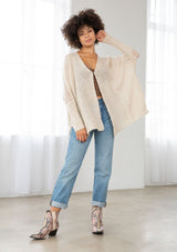 [Color: Oatmeal] A front facing image of a brunette model wearing a knit and lace beige cardigan with a hook and eye closure, batwing sleeves, and slim sleeve finish. A cozy and effortless cardigan for the fall season. 