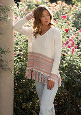 [Color: Off White/Lt Taupe] A blonde model wearing a bohemian fringed beach sweater with long sleeves and a hoodie.