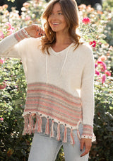 [Color: Off White/Lt Taupe] A blonde model wearing a bohemian fringed beach sweater with long sleeves and a hoodie.