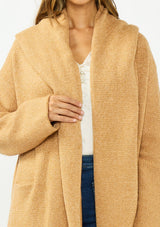[Color: Camel] A detail image of a brunette model wearing a best selling oversized cardigan in a camel brown color. A cozy and thick sweater coat with a hood, an open front, side pockets, a cocoon style silhouette, and a mid length hem. 
