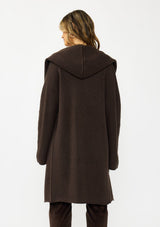 [Color: Chocolate] A back facing image of a brunette model wearing a best selling brown oversized cardigan. A cozy and thick sweater coat with a hood, an open front, side pockets, a cocoon style silhouette, and a mid length hem. 