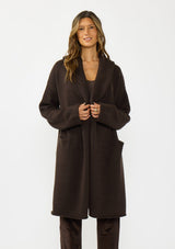 [Color: Chocolate] A front facing image of a brunette model wearing a best selling brown oversized cardigan. A cozy and thick sweater coat with a hood, an open front, side pockets, a cocoon style silhouette, and a mid length hem. 