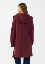 [Color: Wine] A back facing image of a brunette model wearing a best selling burgundy oversized cardigan. A cozy and thick sweater coat with a hood, an open front, side pockets, a cocoon style silhouette, and a mid length hem. 
