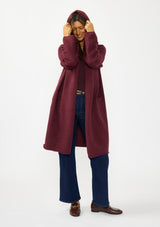 [Color: Wine] A front facing image of a brunette model wearing a best selling burgundy oversized cardigan. A cozy and thick sweater coat with a hood, an open front, side pockets, a cocoon style silhouette, and a mid length hem. 