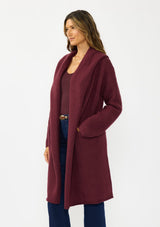 [Color: Wine] A side facing image of a brunette model wearing a best selling burgundy oversized cardigan. A cozy and thick sweater coat with a hood, an open front, side pockets, a cocoon style silhouette, and a mid length hem. 