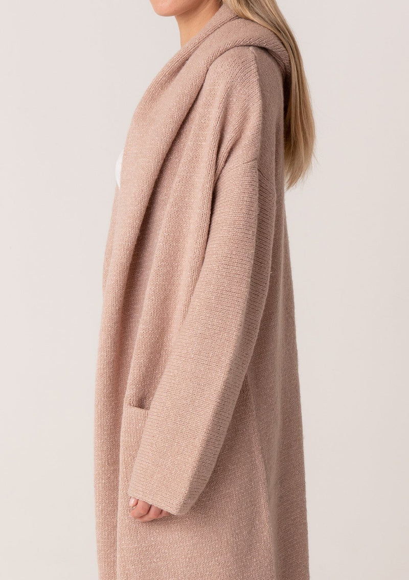 [Color: Heather Rose] A close up side facing image of a blonde model wearing a best selling oversized cardigan in a light pink color. A cozy and thick sweater coat with a hood, an open front, side pockets, a cocoon style silhouette, and a mid length hem. 