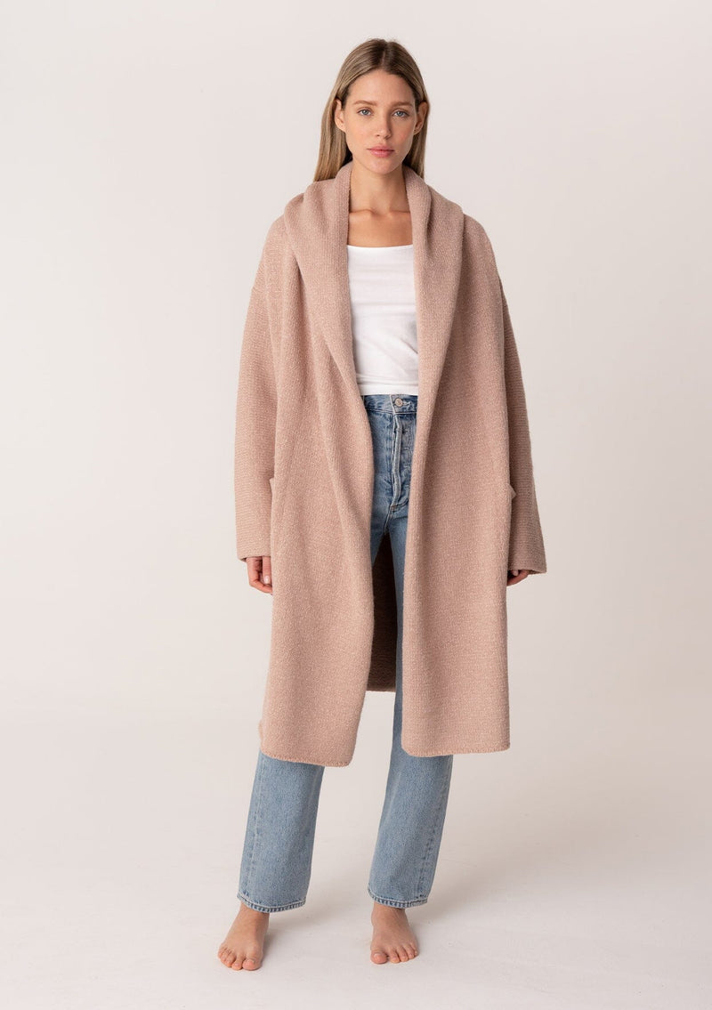 [Color: Heather Rose] A full body front facing image of a blonde model wearing a best selling oversized cardigan in a light pink color. A cozy and thick sweater coat with a hood, an open front, side pockets, a cocoon style silhouette, and a mid length hem. 