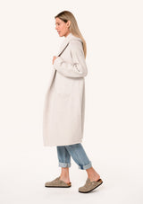 [Color: Oyster] A side facing image of a blonde model wearing a best selling oversized light grey cardigan. A cozy and thick sweater coat with a hood, an open front, side pockets, a cocoon style silhouette, and a mid length hem.