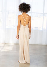 [Color: Natural/Olive/Coral] A back facing image of a brunette model wearing a beige sleeveless maxi dress with a cross back detail.
