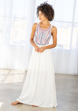 [Color: Off White/Blue/Red] A front facing image of a brunette model wearing a white sleeveless maxi dress with a blue and red embroidered bodice and a scoop neckline. 