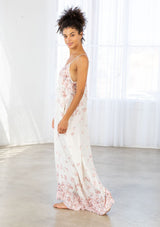 [Color: Blue Rose/Vanilla] A side facing image of a brunette model wearing a bohemian white and pink butterfly print maxi dress with a v neckline and adjustable spaghetti straps. 