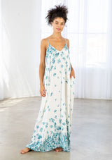 [Color: Hazel Teal/Vanilla] A front facing image of a brunette model wearing a bohemian white and blue butterfly print maxi dress with a v neckline and adjustable spaghetti straps. 