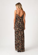 [Color: Black/Taupe] A back facing image of a blonde model wearing a best selling sleeveless maxi dress in a brown bohemian print. With adjustable spaghetti straps, a deep v neckline in the front and back, side pockets, and a flowy cocoon fit. 