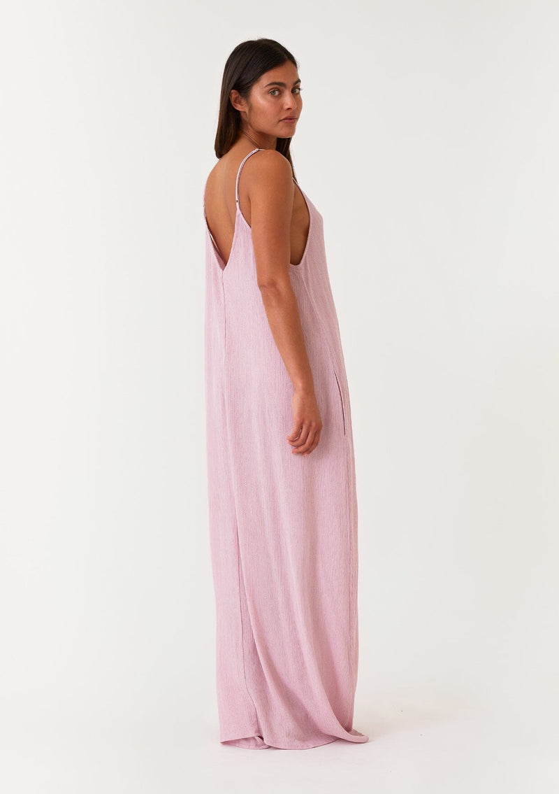 [Color: Orchid] A full body back facing image of a brunette model wearing an orchid purple sleeveless maxi dress with gold metallic thread details. With adjustable spaghetti straps, a deep v neckline in the front and back, side pockets, and a loose, oversized flowy fit. 