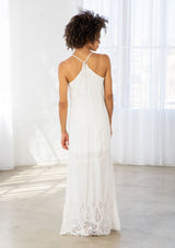 [Color: Off White] A back facing image of a woman wearing a white maxi dress with a white embroidered hem, a scoop neckline, lace trims, and a tie back detail. 