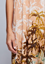 [Color: Peach] A detail image of a brunette model wearing a tropical print maxi dress with a relaxed fit, v neckline, and adjustable spaghetti straps. 