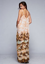 [Color: Peach] A back facing image of a brunette model wearing a tropical print maxi dress with a relaxed fit, v neckline, and adjustable spaghetti straps. 