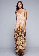 [Color: Peach] A front facing image of a brunette model wearing a tropical print maxi dress with a relaxed fit, v neckline, and adjustable spaghetti straps. 