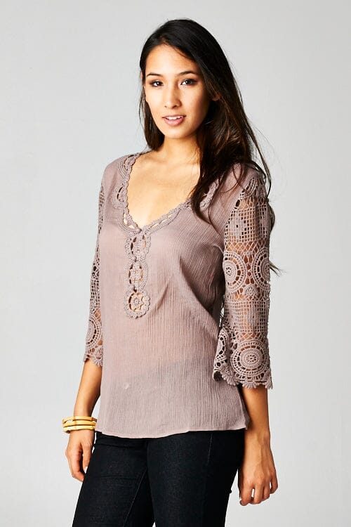 [Color: Dusty Orchid] A front facing image of a brunette model wearing a 3-4 sleeve cotton blouse with delicate crochet lace details. 