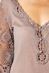 [Color: Dusty Orchid] A detail image of a brunette model wearing a 3-4 sleeve cotton blouse with delicate crochet lace details. 