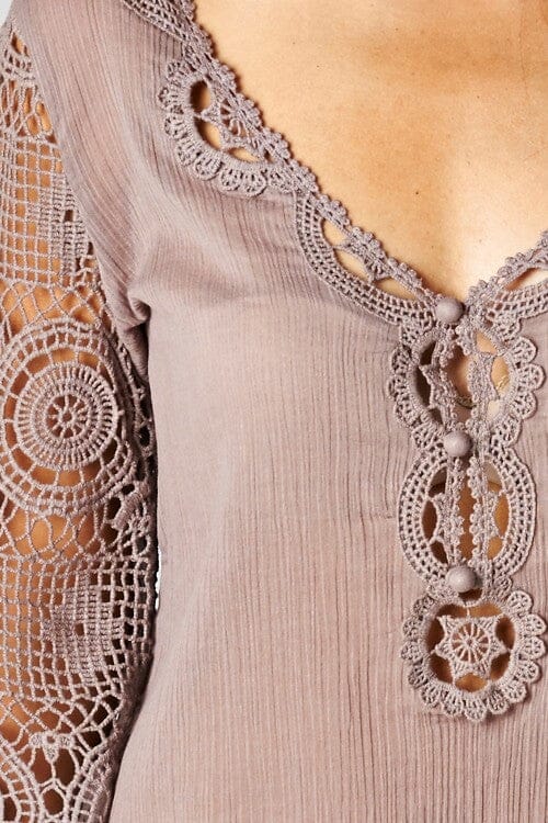[Color: Dusty Orchid] A detail image of a brunette model wearing a 3-4 sleeve cotton blouse with delicate crochet lace details. 