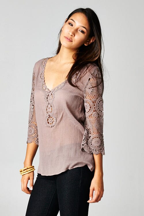 [Color: Dusty Orchid] A front facing image of a brunette model wearing a 3-4 sleeve cotton blouse with delicate crochet lace details. 
