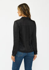 [Color: Black] A back facing image of a brunette model wearing a black satin blouse with a collar, v-neckline, button front, and long sleeves. 