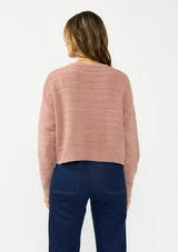 [Color: Rose] A back facing image of a brunette model wearing a dusty pink chenille sweater with a round neck and long sleeves with dropped shoulders. Styled with a dark wash denim with patch pockets.