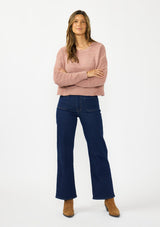 [Color: Rose] A front facing image of a brunette model wearing a dusty pink chenille sweater with a round neck and long sleeves with dropped shoulders. Styled with a dark wash denim with patch pockets.