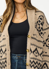 [Color: Taupe/Black] A detail image of a brunette model wearing a brown and black button front cardigan with a southwestern pattern. 