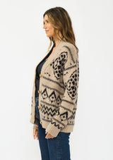 [Color: Taupe/Black] A side facing image of a brunette model wearing a brown and black button front cardigan with a southwestern pattern. 