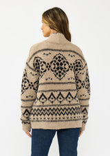 [Color: Taupe/Black] A back facing image of a brunette model wearing a brown and black button front cardigan with a southwestern pattern. 